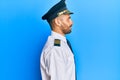 Handsome man with beard wearing airplane pilot uniform looking to side, relax profile pose with natural face with confident smile