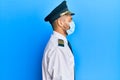 Handsome man with beard wearing airplane pilot uniform wearing safety mask looking to side, relax profile pose with natural face