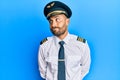 Handsome man with beard wearing airplane pilot uniform smiling looking to the side and staring away thinking Royalty Free Stock Photo