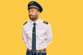 Handsome man with beard wearing airplane pilot uniform smiling looking to the side and staring away thinking Royalty Free Stock Photo