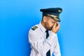 Handsome man with beard wearing airplane pilot uniform tired rubbing nose and eyes feeling fatigue and headache Royalty Free Stock Photo