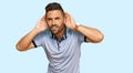 Handsome man with beard wearing casual clothes trying to hear both hands on ear gesture, curious for gossip Royalty Free Stock Photo