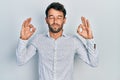 Handsome man with beard wearing casual elegant shirt relax and smiling with eyes closed doing meditation gesture with fingers Royalty Free Stock Photo