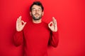 Handsome man with beard wearing casual red sweater relaxed and smiling with eyes closed doing meditation gesture with fingers Royalty Free Stock Photo