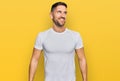 Handsome man with beard wearing casual white t shirt looking away to side with smile on face, natural expression Royalty Free Stock Photo