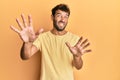 Handsome man with beard wearing casual yellow tshirt over yellow background afraid and terrified with fear expression stop gesture Royalty Free Stock Photo