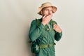 Handsome man with beard wearing explorer hat and backpack bored yawning tired covering mouth with hand Royalty Free Stock Photo