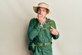 Handsome man with beard wearing explorer hat and backpack looking stressed and nervous with hands on mouth biting nails Royalty Free Stock Photo