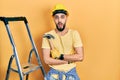 Handsome man with beard wearing hardhat holding hammer by stairs afraid and shocked with surprise and amazed expression, fear and Royalty Free Stock Photo