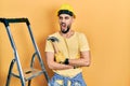 Handsome man with beard wearing hardhat holding hammer by stairs angry and mad screaming frustrated and furious, shouting with Royalty Free Stock Photo
