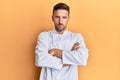 Handsome man with beard wearing professional cook uniform skeptic and nervous, disapproving expression on face with crossed arms