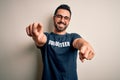 Handsome man with beard wearing t-shirt with volunteer message over white background pointing to you and the camera with fingers, Royalty Free Stock Photo