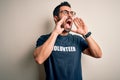 Handsome man with beard wearing t-shirt with volunteer message over white background Shouting angry out loud with hands over mouth