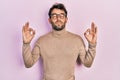Handsome man with beard wearing turtleneck sweater and glasses relax and smiling with eyes closed doing meditation gesture with Royalty Free Stock Photo