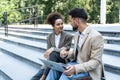 Handsome man and beautiful woman working on wireless laptop near office center. Two business people colleagues sitting on stairs Royalty Free Stock Photo