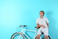 Handsome man with bicycle against color background