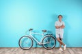 Handsome man with bicycle against color wall
