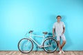 Handsome man with bicycle against color wall