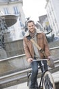 Handsome man with a bicycle with fountain in background