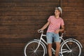 Handsome man with bicycle near wooden wall