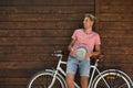 Handsome man with bicycle near wooden wall