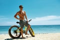 Handsome Man With Bike Sun Tanning On Beach. Summer Vacation.