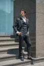 Handsome man in black formal suit and yellow sunglasses standing on the stairs and keeping his hands in his pockets. Royalty Free Stock Photo