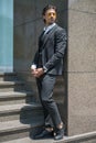 Handsome man in black formal suit and yellow sunglasses standing on the stairs and keeping his hands in his pockets. Royalty Free Stock Photo