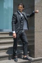 Handsome man in black formal suit and yellow sunglasses standing on the stairs and keeping his hands in his pockets. Royalty Free Stock Photo