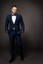 Handsome Man in Black Suit, Elegant Fashion Model Studio Portrait in Tuxedo, Hands in Pockets Royalty Free Stock Photo