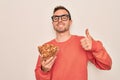 Handsome man with blue eyes holding bowl with healthy almonds snack over white background happy with big smile doing ok sign, Royalty Free Stock Photo