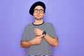 Handsome man with blue eyes wearing striped t-shirt and french beret over purple background In hurry pointing to watch time, Royalty Free Stock Photo