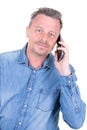 Handsome man in blue shirt talking on smartphone phone standing in front of white background studio Royalty Free Stock Photo