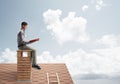 Handsome man on brick roof against cloud scape reading book Royalty Free Stock Photo