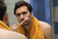 Handsome man brushing teeth and looking at the mirror in the bathroom Royalty Free Stock Photo