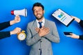 Handsome man business with beard working at the office being stressed out smiling with hands on chest, eyes closed with grateful