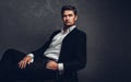 Handsome man in a business suit sits on a chair and looks away, portrait