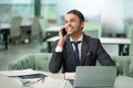 Handsome man in business suit talking on the phone working on laptop, job in progress. Cheer smiling freelancer making Royalty Free Stock Photo