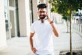 Handsome indian man cell phone call smile outdoor city street. Young attractive businessman casual blue shirt talking Royalty Free Stock Photo