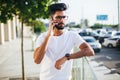 Handsome indian man cell phone call smile outdoor city street. Young attractive businessman casual blue shirt talking Royalty Free Stock Photo