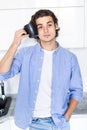 Handsome young man with coffee cup near head, suffer from pain, in the morning at kitchen Royalty Free Stock Photo