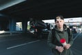 A handsome man with coffee hands standing against the back of the road and cars under the bridge and looking at the camera Royalty Free Stock Photo