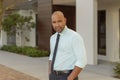 A handsome man of color dressed in professional clothing in front of a downtown building