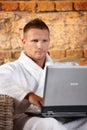 Handsome man with computer in bathrobe Royalty Free Stock Photo