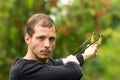 Handsome man concentrated aiming a slingshot at