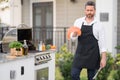 Handsome man in cook apron preparing salmon fish on barbecue grill outdoor. Man cooking tasty food on barbecue grill at Royalty Free Stock Photo