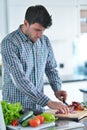 Handsome man cooking at home preparing salad in kitchen. Royalty Free Stock Photo