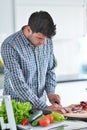 Handsome man cooking at home preparing salad in kitchen. Royalty Free Stock Photo