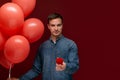 Handsome man with coral balloons and red box with engagement ring Royalty Free Stock Photo