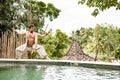 Handsome man in costume practice qigong exercises outdoors in summer terrace near the pool. Healing and spiritual Wellness, Bali,